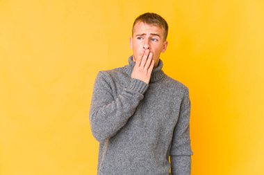 Beyaz tenli yakışıklı adam esniyor. Ağzı eliyle kapatan yorgun bir jest yapıyor..