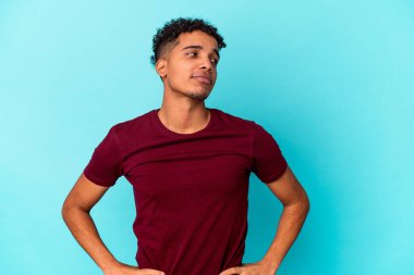 Genç Afro-Amerikalı kıvırcık adam mavi üzerine izole edilmiş, kendine güvenen, kalçaları üzerinde duran..