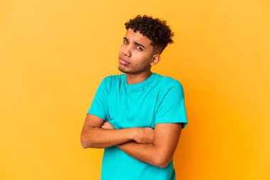 Genç Afro-Amerikalı kıvırcık adam mor üzerine izole edilmiş şüpheli, belirsiz, seni inceliyor..