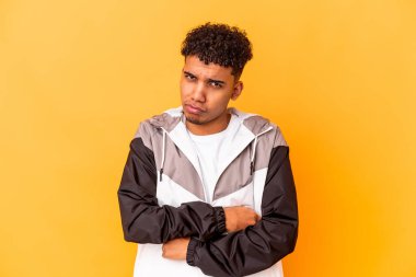 Genç Afro-Amerikalı kıvırcık adam, morarmış kaşlarını çatmış, kollarını kavuşturmuş..