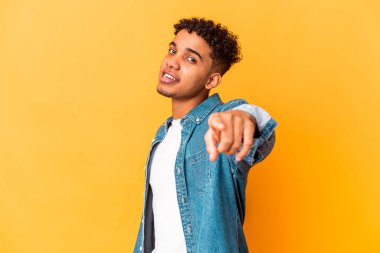 Genç Afro-Amerikalı kıvırcık adam, mor üzerine izole edilmiş, parmaklarıyla öne doğru işaret ediyor..