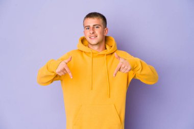 Beyaz tenli yakışıklı adam parmaklarıyla aşağı işaret ediyor, olumlu bir his..