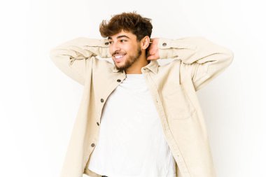 Beyaz arka planda genç bir Arap kendini güvende hissediyor, elleri başının arkasında..