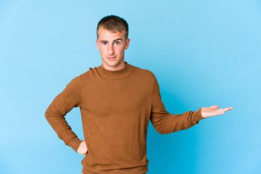 Beyaz tenli yakışıklı bir adam avucunun içinde fotokopi odası gösteriyor ve elini beline koyuyor..