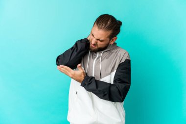 Uzun saçlı genç adam kötü bir hareketin ardından acı çeken dirsek masajı yapıyor..