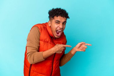 Genç Afro-Amerikan kıvırcık adamı mavi üzerine izole edilmiş, işaret parmağıyla fotokopi çekerek heyecan ve arzusunu ifade ediyor..
