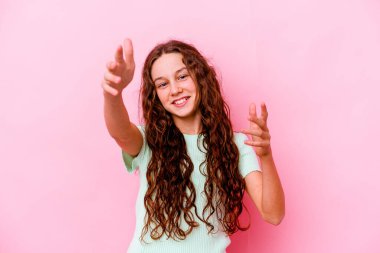 Pembe arka planda izole edilmiş küçük beyaz kız kameraya sarılıyor..