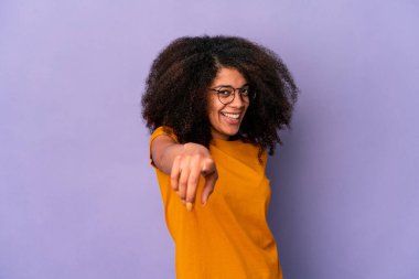 Genç Afro-Amerikalı kıvırcık kadın. Mor arka planda soyutlanmış. Neşeli gülümsemeler ön tarafı işaret ediyor..