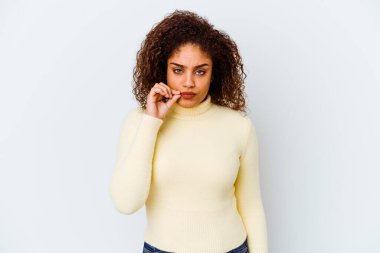 Genç Afrikalı Amerikalı kadın beyaz arka planda izole edilmiş, parmakları dudaklarında bir sır saklıyor..