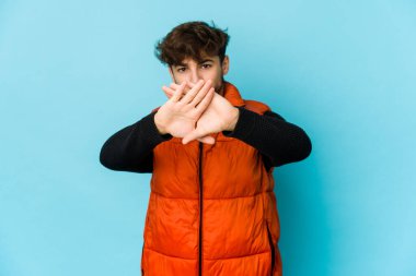 Mavi arka plandaki genç Arap adam elini uzatıp dur işareti göstererek seni engelliyor..