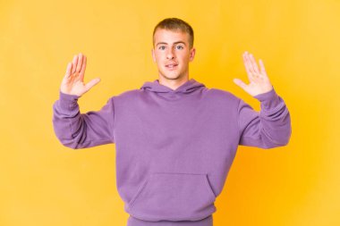 Kafkasyalı yakışıklı genç adam işaret parmaklarıyla küçük bir şey tutuyor, gülümsüyor ve kendinden emin..