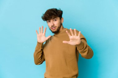 Mavi arka plandaki genç Arap, yakın bir tehlike nedeniyle şoka uğruyor.