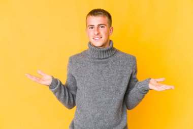 Genç, beyaz, yakışıklı adam kollarıyla ölçü yapıyor, mutlu ve kendinden emin..