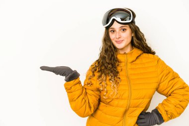 Beyaz tenli genç bir snowboardcu, izole edilmiş bir şekilde bir palmiyenin üzerinde fotokopi alanı gösteriyor ve belinde bir el daha tutuyor..