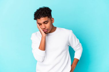 Genç Afro-Amerikalı kıvırcık adam mavi üzerine izole edilmiş sıkılmış, yorgun ve dinlenmeye ihtiyacı var..