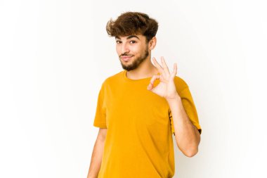 Beyaz arka plandaki genç Arap bir göz kırptı ve elleriyle iyi bir jest yaptı..