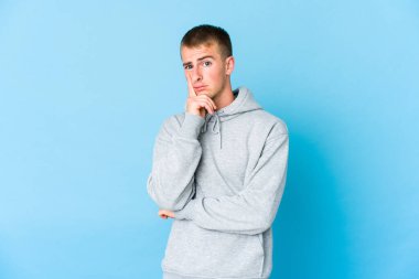 Genç, beyaz, yakışıklı, mutsuz, iğneleyici bir ifadeyle kameraya bakıyor..