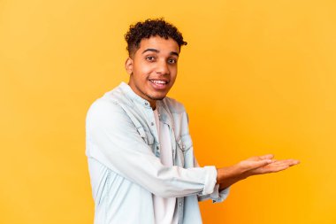 Genç Afro-Amerikalı kıvırcık adam, mor üzerine izole edilmiş. Elinde palmiye ağacında bir kopya alanı var..