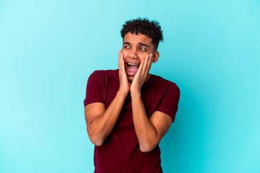 Genç Afro-Amerikalı kıvırcık adam mavi üzerine izole edilmiş korkmuş ve korkmuş.