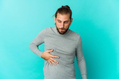 Uzun saçlı genç adam karnına dokunuyor, nazikçe gülümsüyor, yemek yiyor ve tatmin oluyor..