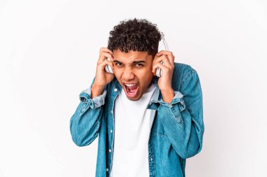 Genç Afro-Amerikalı kıvırcık adam kulaklarını elleriyle kapatan kulaklıklarla müzik dinliyor..