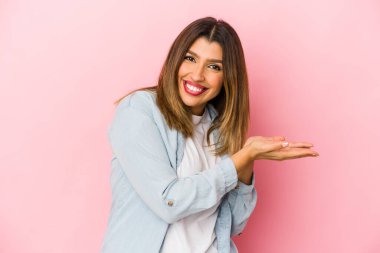 Pembe arka planda izole edilmiş genç Hintli kadın avucunun içinde bir kopya alanı tutuyor..