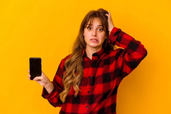 Junge Kaukasische Frau Hält Telefon Isoliert Auf Gelbem Hintergrund Schockiert — Stockfoto