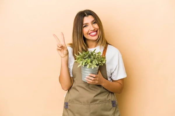 Jovem Indiana Jardineiro Mulher Segurando Uma Planta Isolada Mostrando Número — Fotografia de Stock