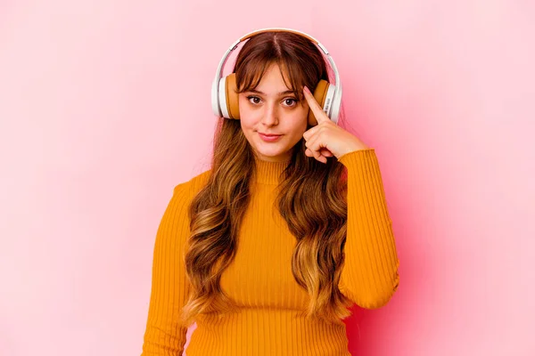 Mujer Caucásica Joven Escuchando Música Con Auriculares Aislados Apuntando Templo — Foto de Stock