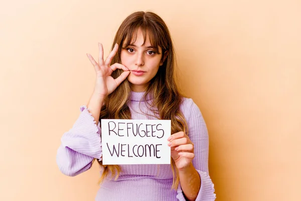 難民を抱えている若い白人女性が秘密のまま唇に指で隔離された歓迎のプラカード — ストック写真