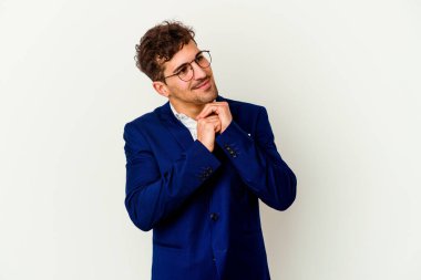 Beyaz arka planda izole genç beyaz iş adamı ellerini çenesinin altında tutuyor, mutlu bir şekilde yana bakıyor..