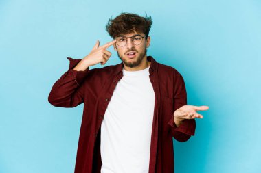 Mavi arka plandaki genç Arap adam elinde bir ürün tutuyor ve.