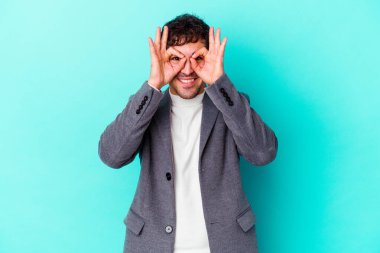 Kafkasyalı genç adam mavi arka planda izole edildi. Heyecanlı görünüyor..