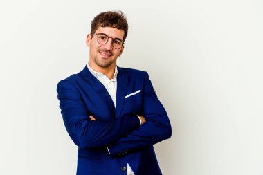 Beyaz arka planda kendini güvende hisseden, kararlılıkla kollarını kavuşturan beyaz tenli genç bir adam..