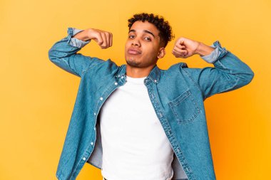 Genç Afro-Amerikan kıvırcık adamı, mor üzerine izole edilmiş, güçlü hareketini kollarıyla gösteriyor, kadınsı gücün sembolü.