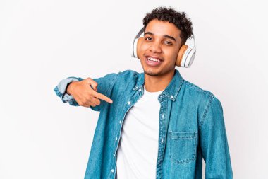Genç Afro-Amerikalı kıvırcık adam kulaklıkla müzik dinleyip gömlek fotokopi alanını işaret ediyor, gururlu ve kendinden emin.