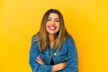 Sarı arka planda yalnız yaşayan genç Hintli kadın gülüyor ve eğleniyor..