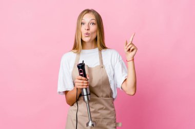 Genç Rus aşçı kadın elinde elektrikli mikser tutuyor. Harika bir fikri var, yaratıcılık kavramı..