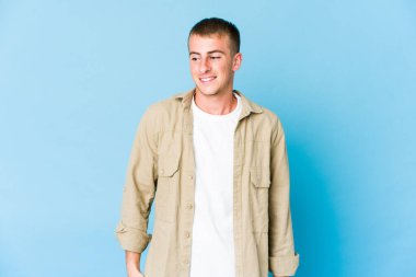 Genç beyaz yakışıklı adam gülüyor ve gözlerini kapıyor, rahatlamış ve mutlu hissediyor..