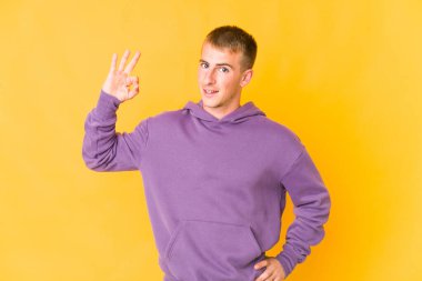 Beyaz tenli yakışıklı bir adam göz kırptı ve elleriyle iyi bir jest yaptı..