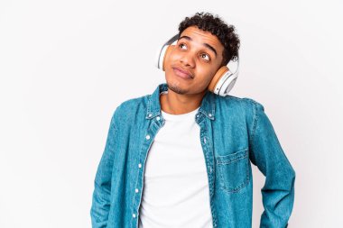 Genç Afro-Amerikan kıvırcık adamı kulaklıkla müzik dinleyip amaçlarına ve amaçlarına ulaşmayı hayal ediyor.