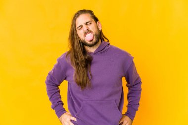 Uzun saçlı genç adam komik ve arkadaş canlısı görünüyor..