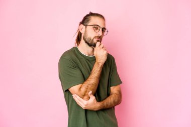 Uzun saçlı genç adam şüpheli ve kuşkulu bir ifadeyle yana bakıyor..