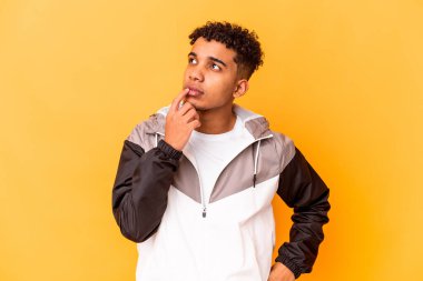 Genç Afro-Amerikan kıvırcık adamı, mor renkte izole edilmiş, kuşkulu ve kuşkulu bir ifadeyle yana bakıyor..