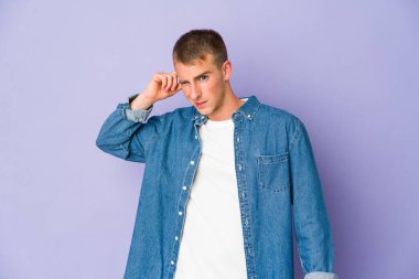 Genç, beyaz, yakışıklı adam kulaklarını elleriyle kapatıyor..