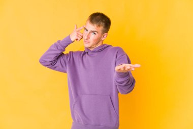 Genç, beyaz, yakışıklı bir adam elinde bir ürün tutuyor..