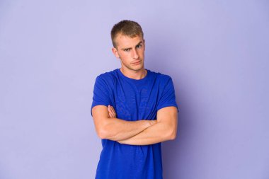 Genç, beyaz, yakışıklı, mutsuz, iğneleyici bir ifadeyle kameraya bakıyor..