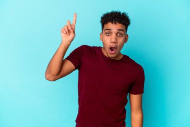 Genç Afro-Amerikan kıvırcık adamı mavi üzerine izole edilmiş. Harika bir fikri var, yaratıcılık kavramı..