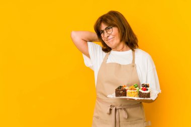 Orta yaşlı Kafkas aşçı kadın başının arkasına dokunuyor, düşünüyor ve bir seçim yapıyor..