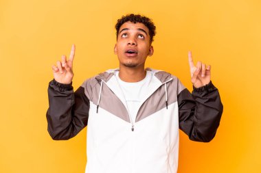 Genç Afro-Amerikalı kıvırcık adam mor renkte, ağzı açık, üst tarafı işaret ediyor..